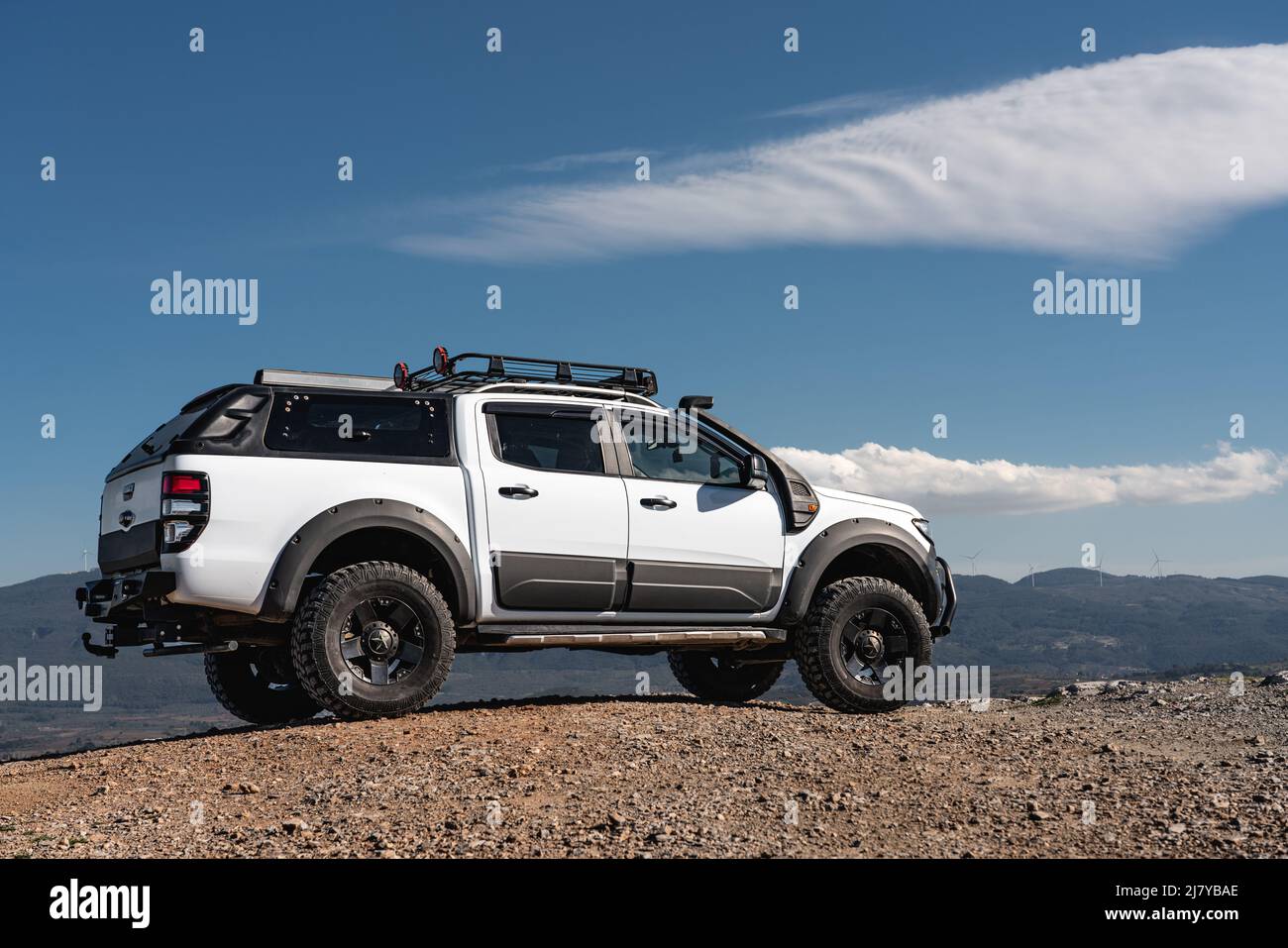 Custom made 4x4 white Ford pickup on the deserted road in the high mountains on the blue sky background. Stock Photo