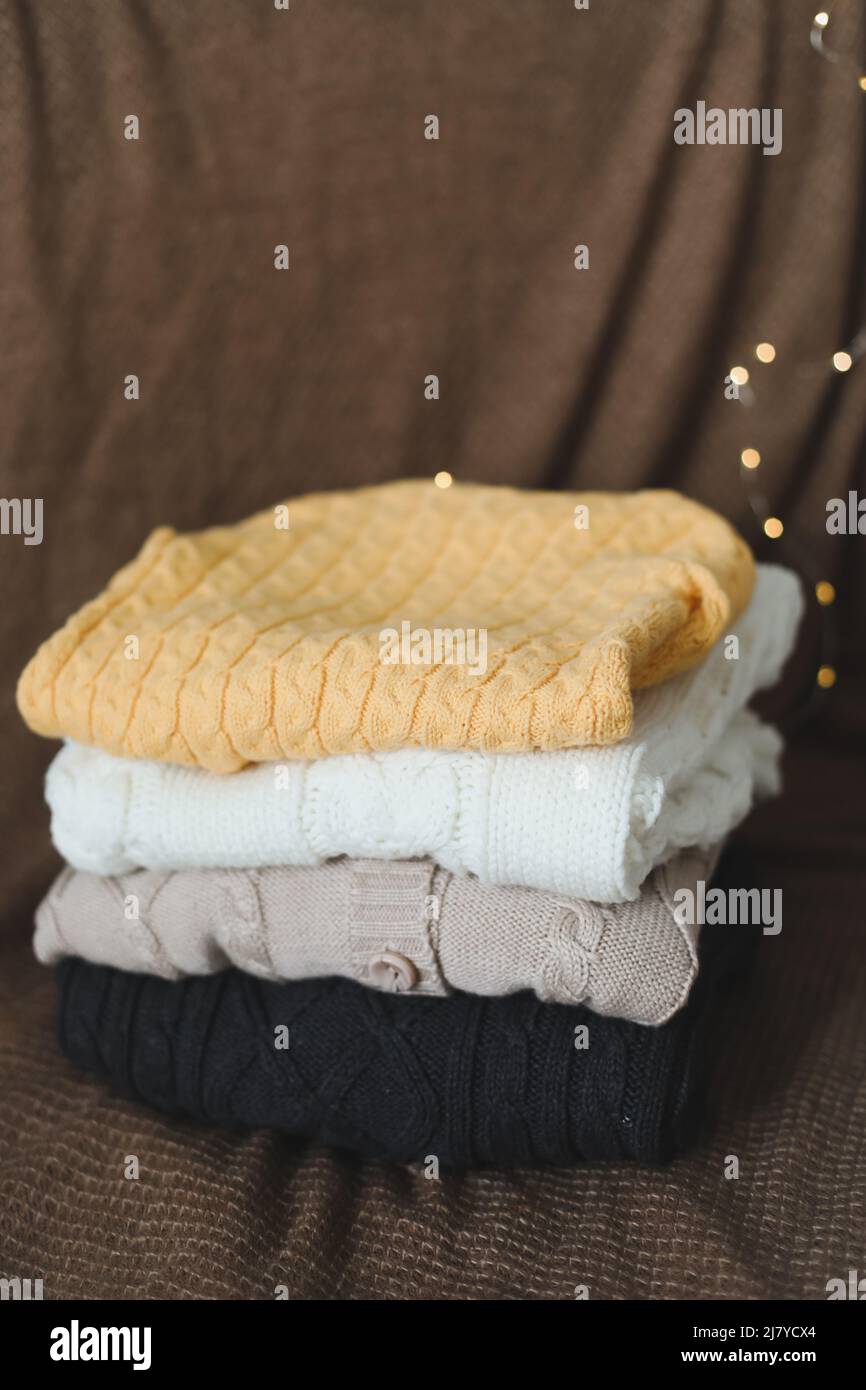 a stack of warm woolen knitted sweaters on a dark background. Stock Photo