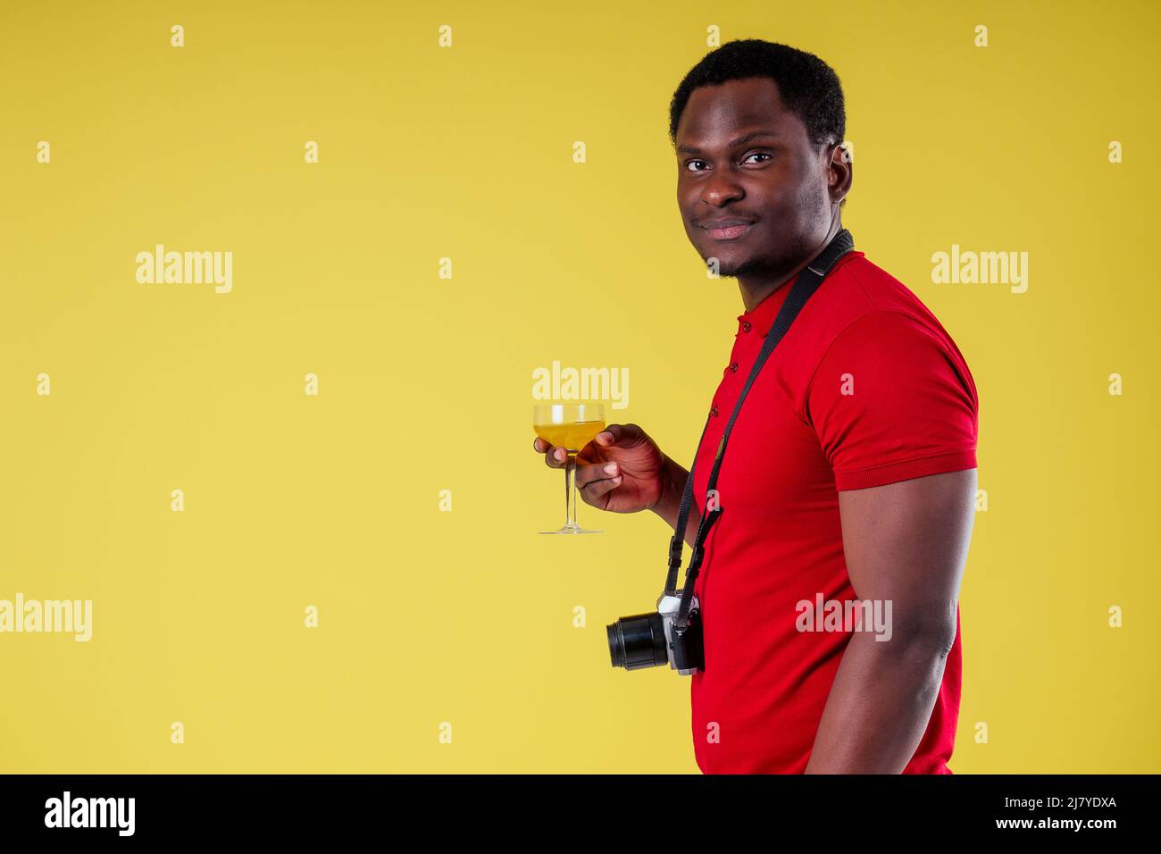 handsome photographer happy young african man Kenya Africa tourist isolated yellow wall background holding tickets with passport and coctail glass and Stock Photo