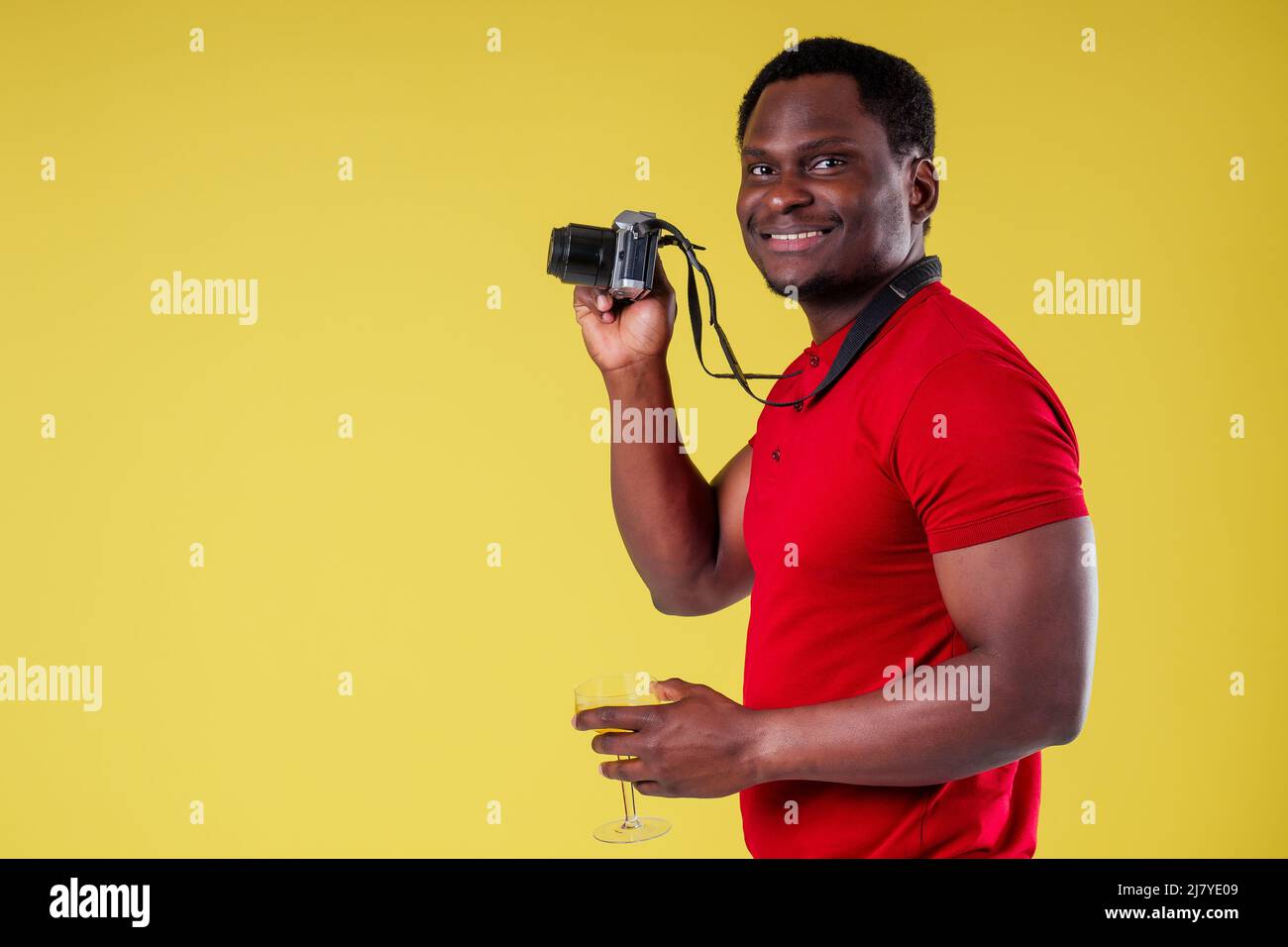 handsome photographer happy young african man Kenya Africa tourist isolated yellow wall background holding tickets with passport and coctail glass and Stock Photo
