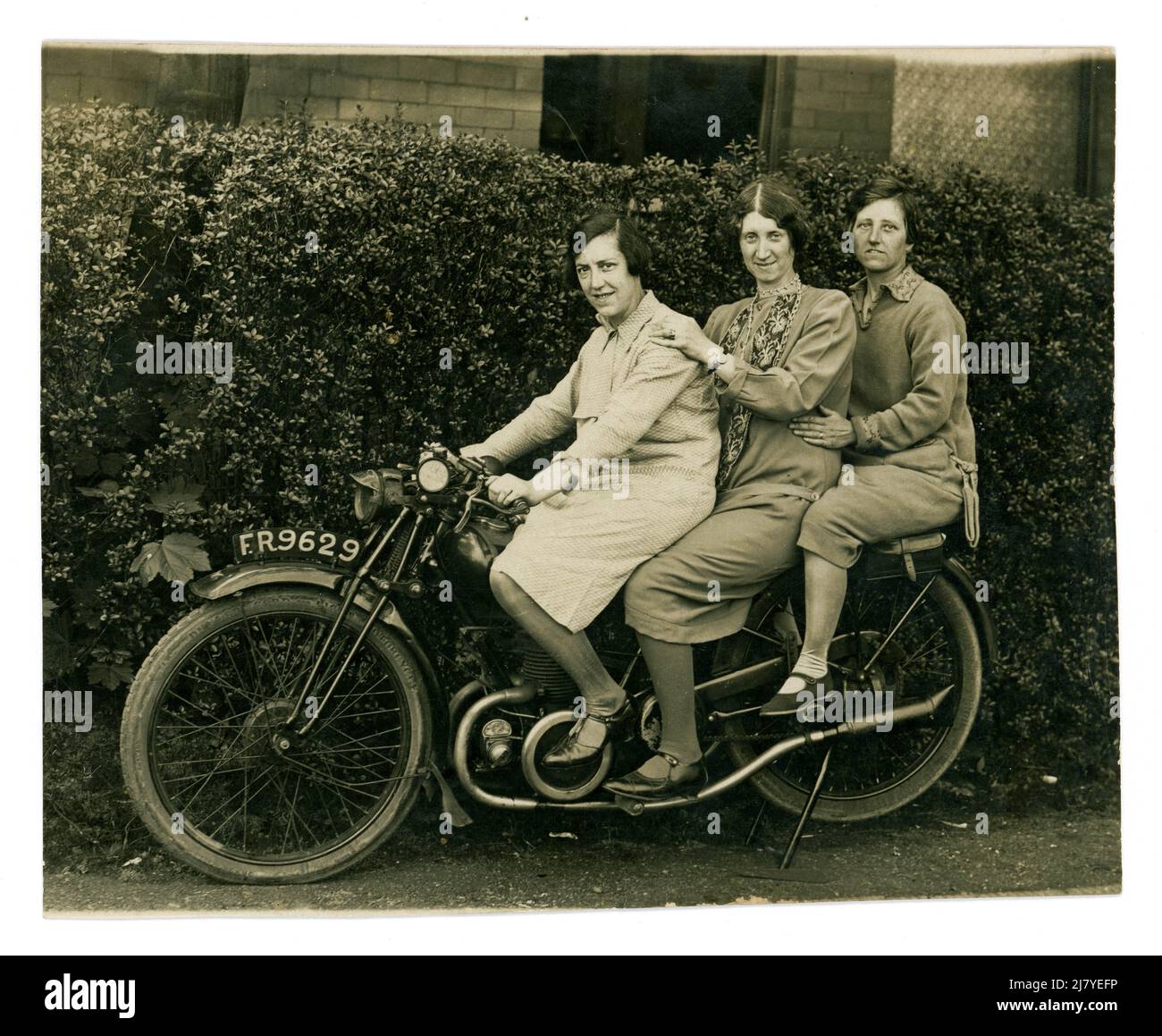 Original, humorous 1920's postcard of 3 mature / middle aged women, friends,  posing sitting together on a motorcycle, riding pillion, enjoying themselves on holiday at the seaside resort of Blackpool, Lancashire, U.K. dated 1 May 1929, Stock Photo