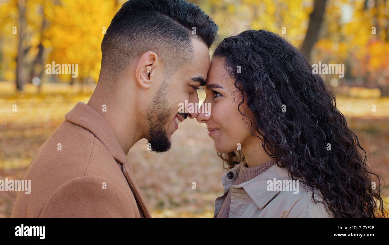 Loving married couple standing foreheads touched and rubbing noses enamored smiling happily outdoors look into each other eyes with love enjoy Stock Photo