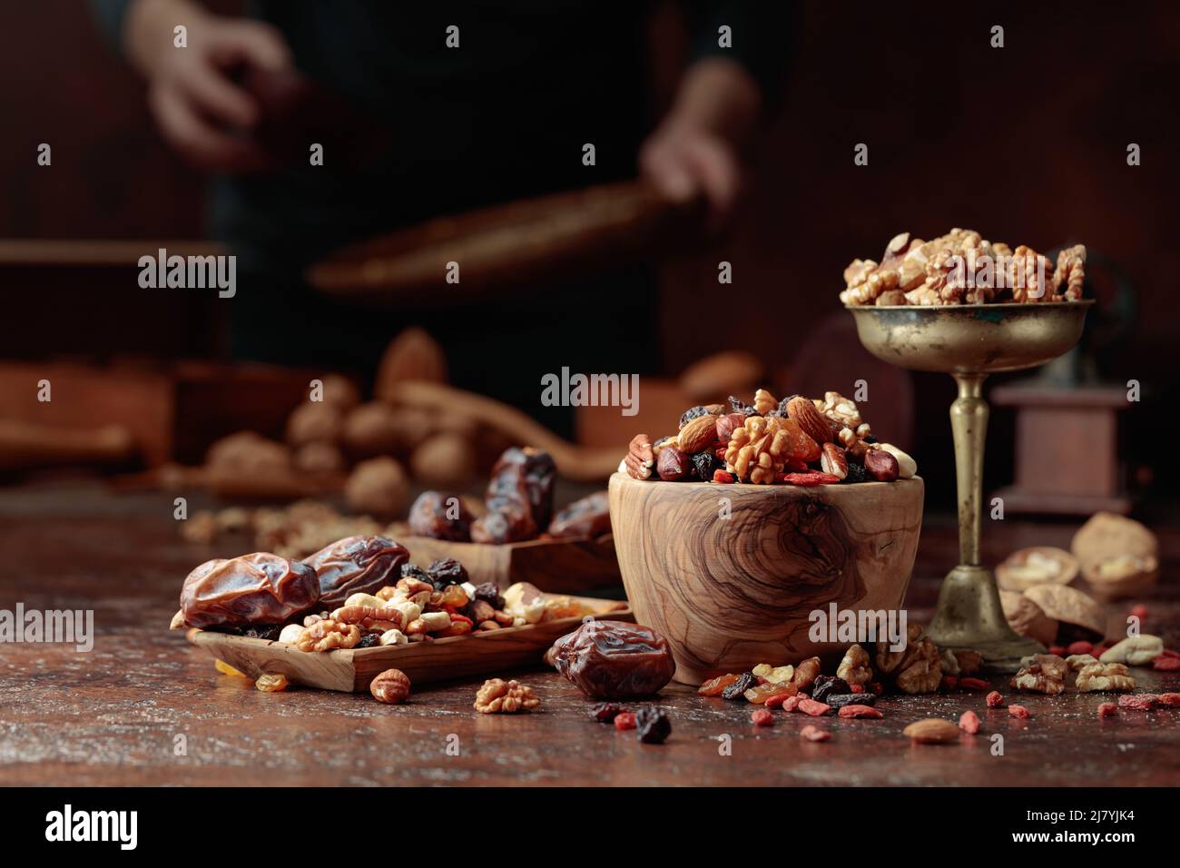 Various dried fruits and nuts are in a wooden bowl on a kitchen table. Selective focus. Stock Photo