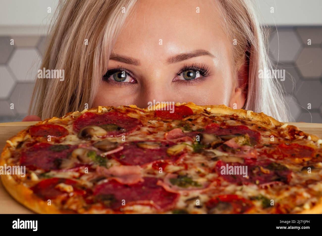 woman openung ovens and cut pizza with tomatoes, olives, mushrooms and cheese sausage Stock Photo