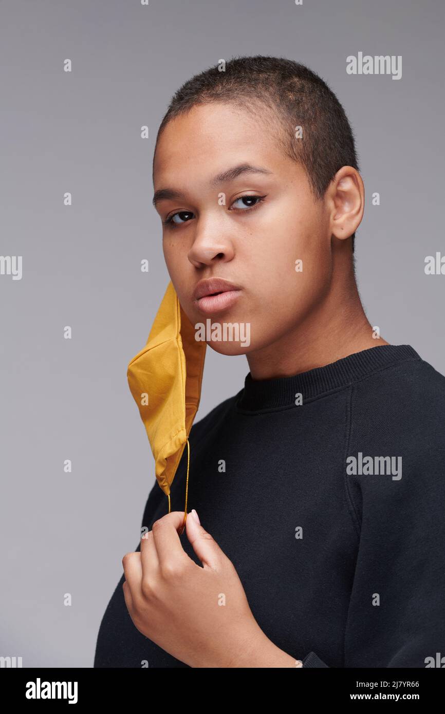 Portrait of shorthaired young black woman with yellow mask hanging on