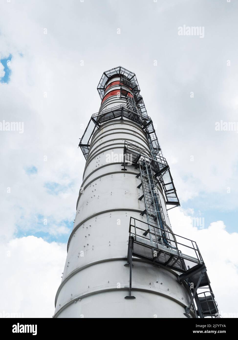 White chimneys of a power plant on a background of clouds with diagonal lines in a vertical frame Stock Photo
