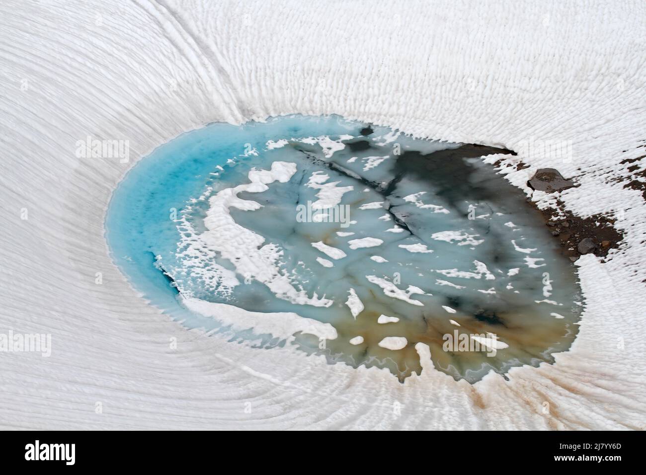 Small lake in snow and ice, during snow melt in swiss alps Stock Photo