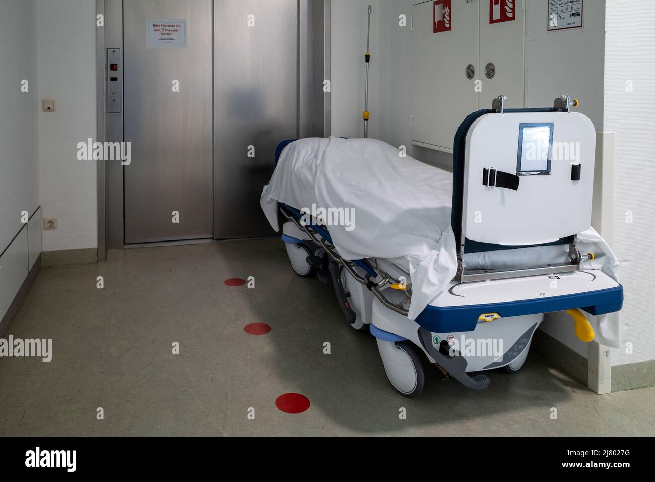 a patient transport bed stands in front of an elevator in a hospital