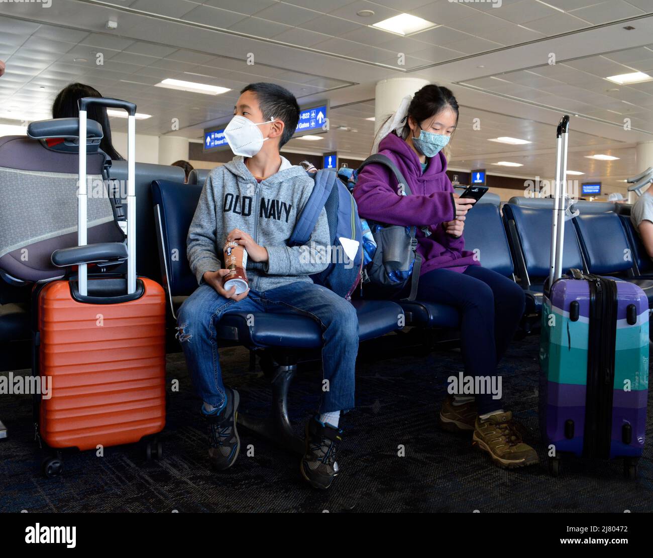 Passengers waiting to board their plane wear face masks as they sit in