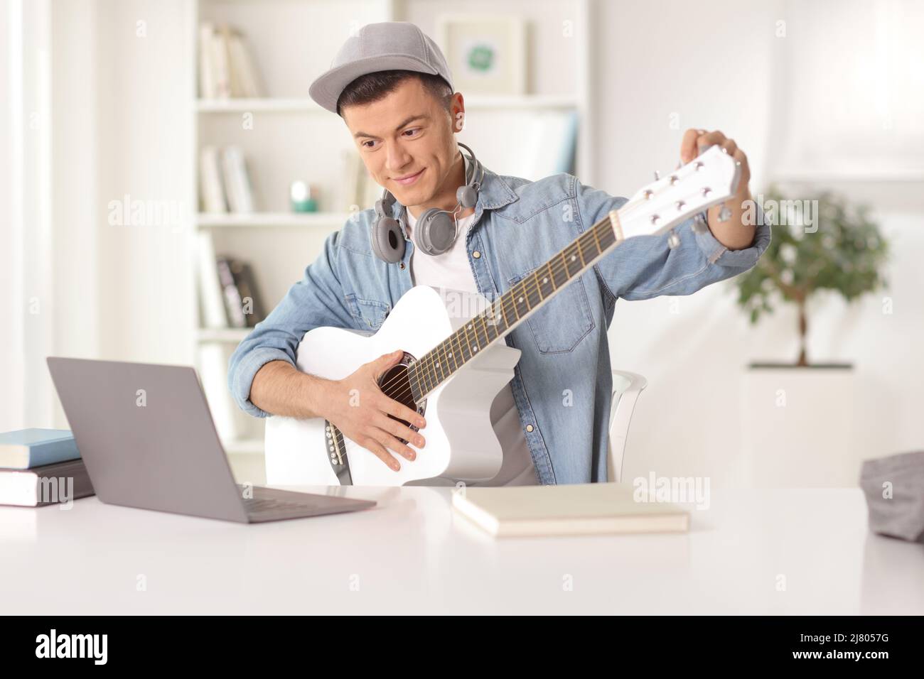 Guy sitting in front of a laptop computer at home and tuning an ...