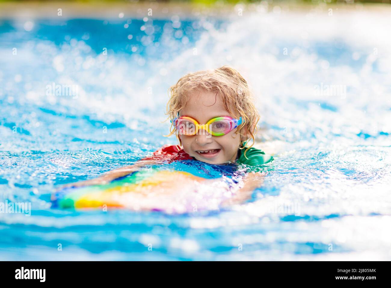 Child learning to swim in outdoor pool of tropical resort. Kids learn ...