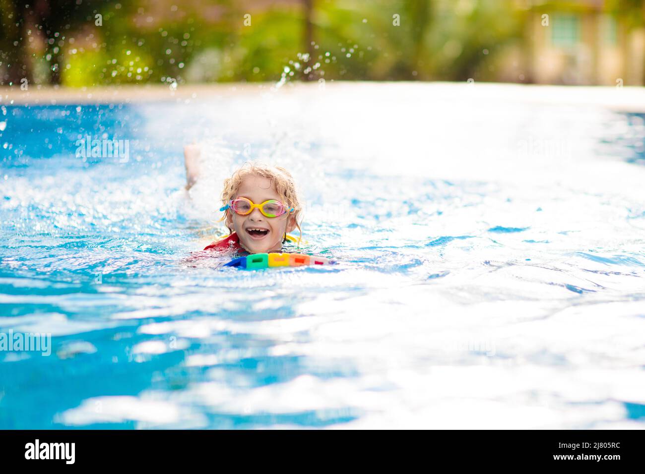 Child learning to swim in outdoor pool of tropical resort. Kids learn