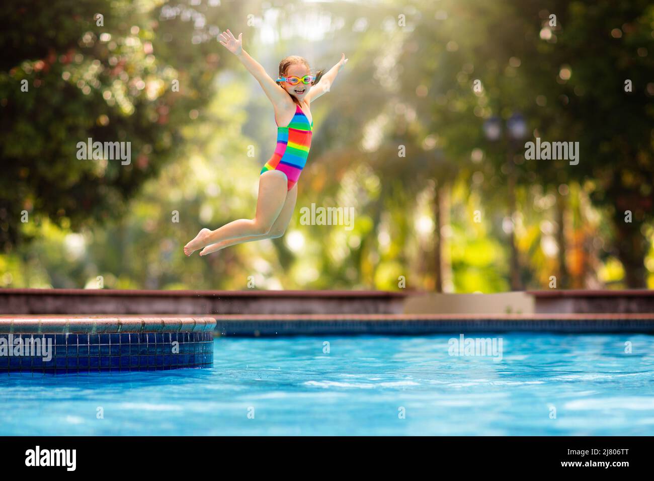 Child jumping and diving in swimming pool. Kids swim, jump and dive