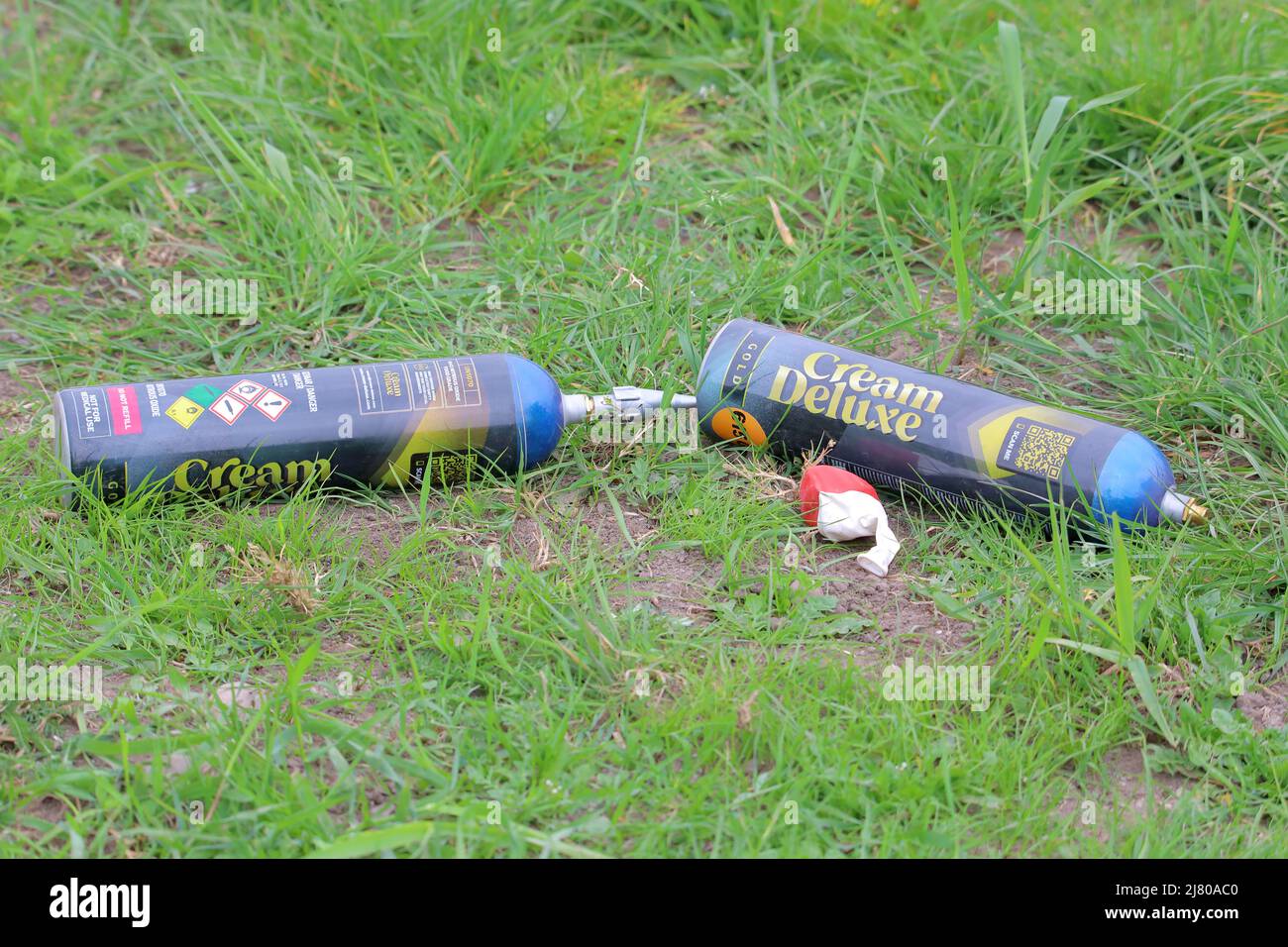 two aerosols cans of nitrous oxide (N2O) and a red and white balloon Stock Photo