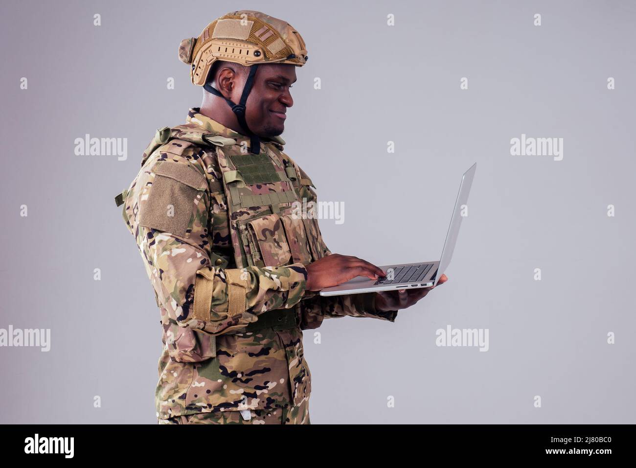 African American soldier smiles while typing a computer videocall with wife and child Stock Photo