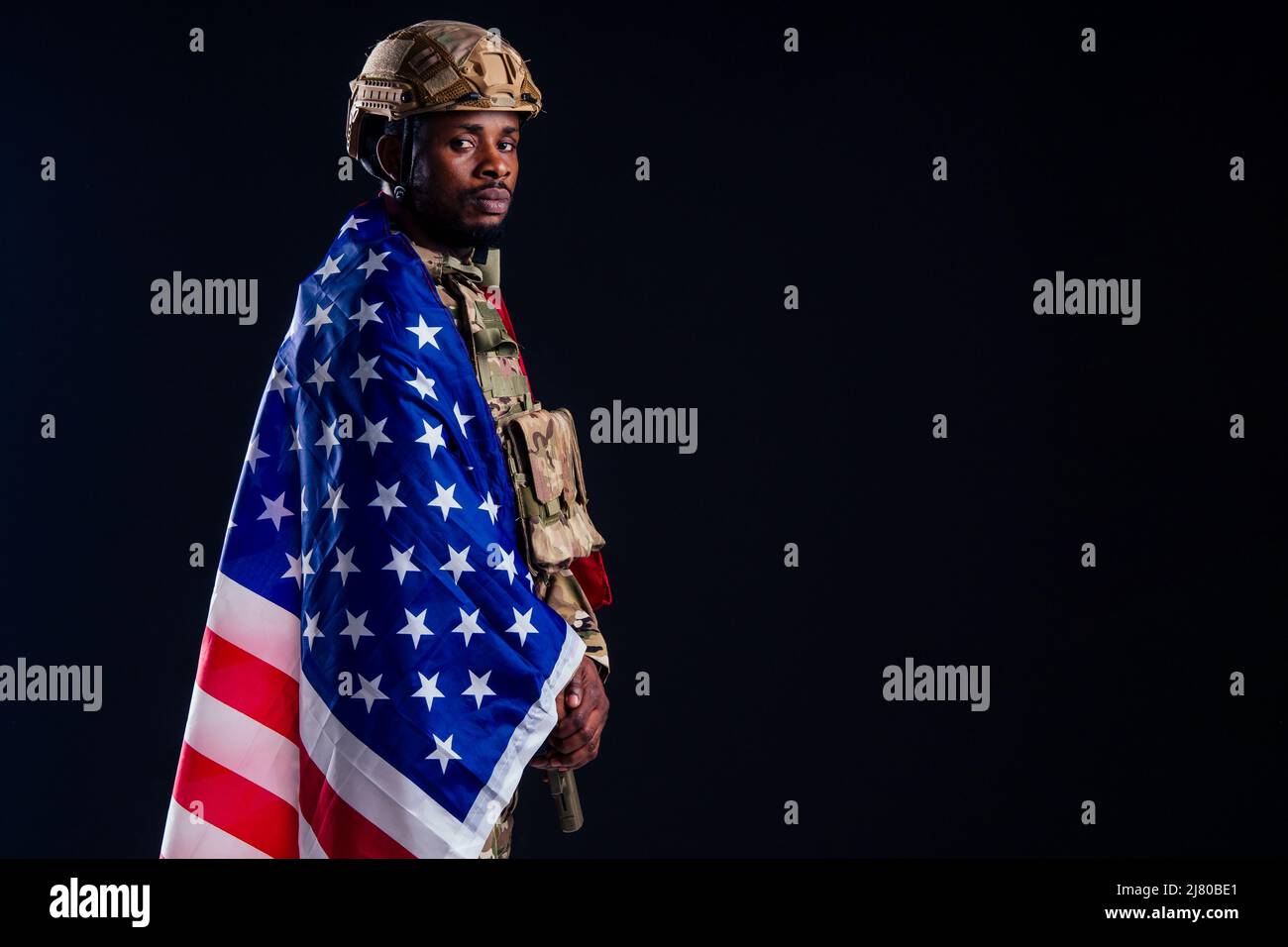 military army african male camouflage suit sorrow wrapped in an American flag black background studio Stock Photo