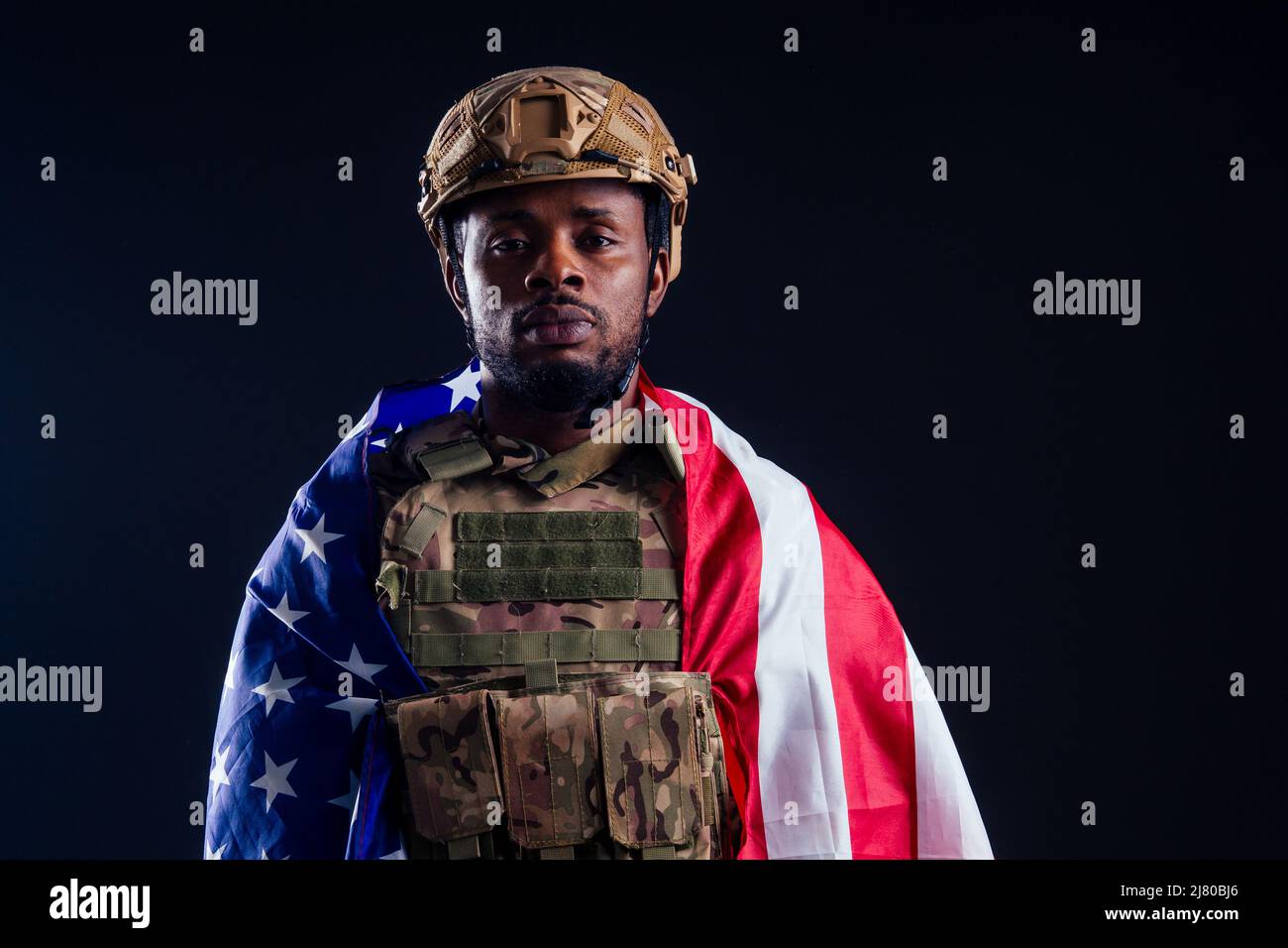 military army african male camouflage suit sorrow wrapped in an American flag black background studio Stock Photo