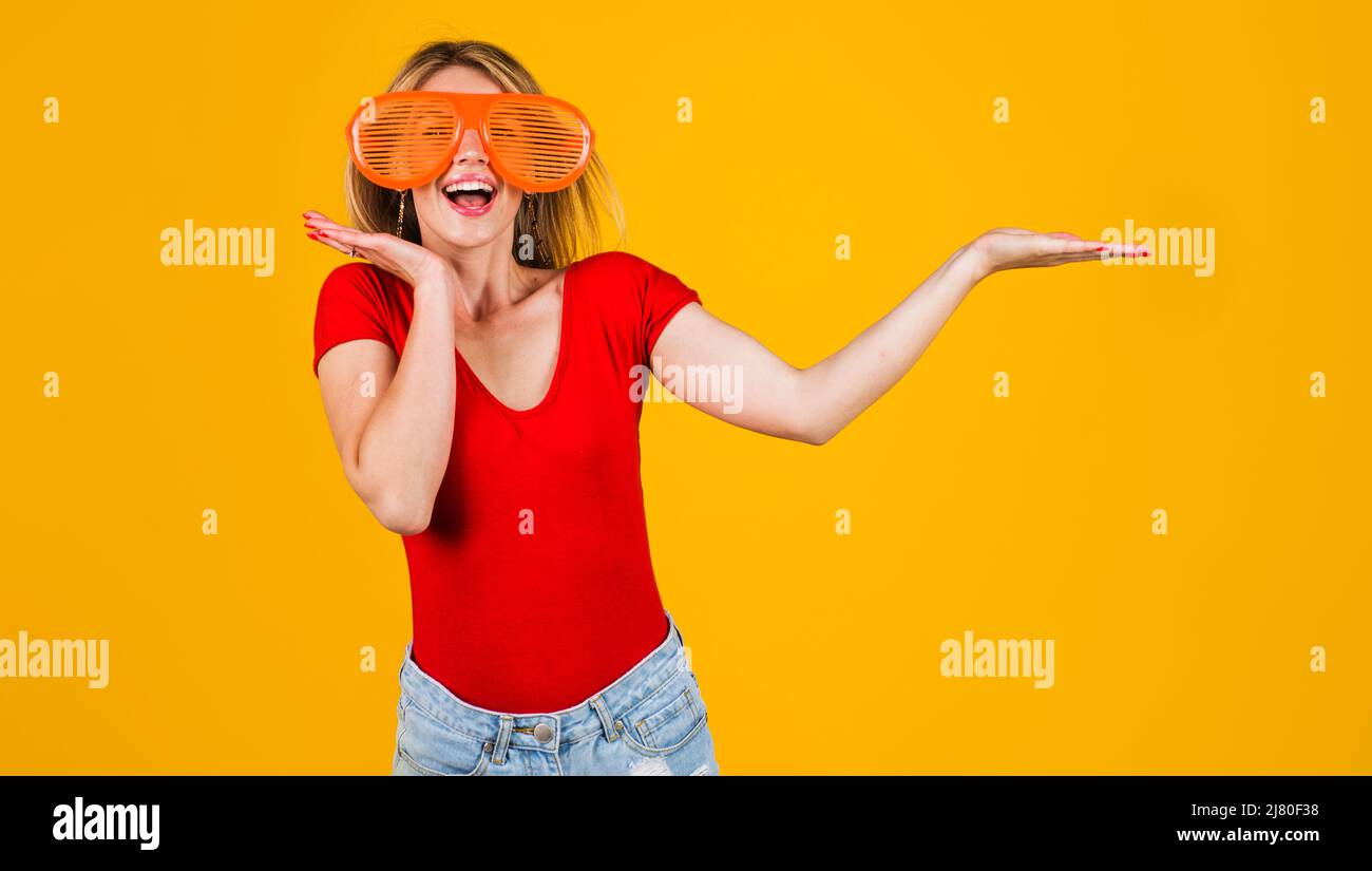 Excited girl holds something on open palm. Season sale and discount. Funny woman in big glasses. Stock Photo