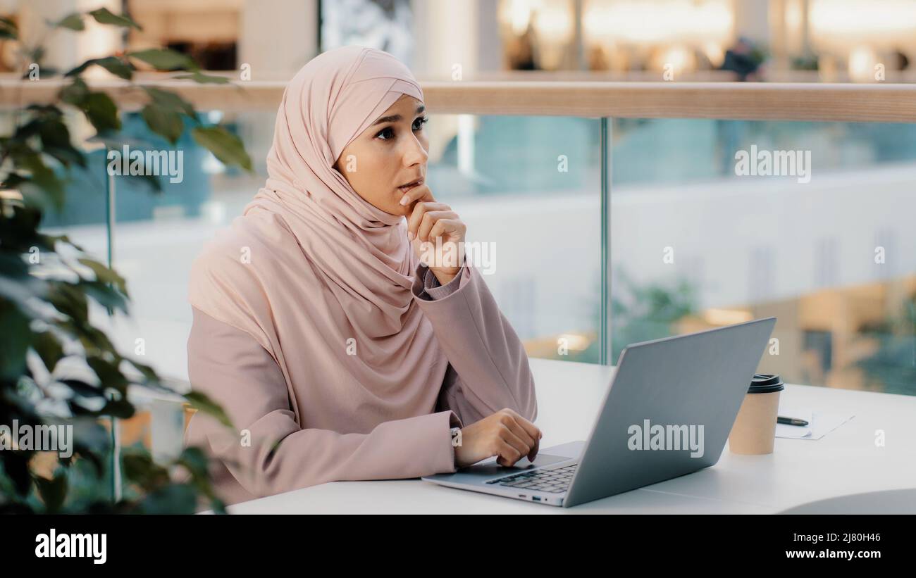 Serious arab woman in hijab working remotely typing on laptop writing book article muslim writer journalist female student creative personality Stock Photo