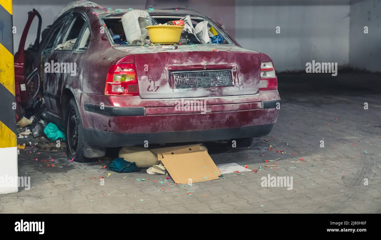 back part of a destroyed car with trash in the underground parking lot full shot. High quality photo Stock Photo