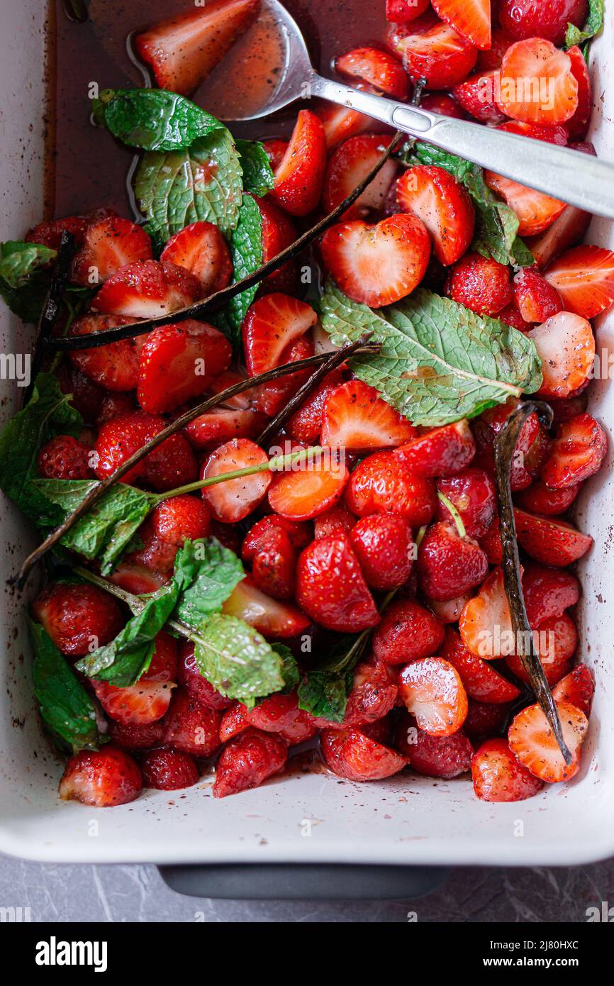 strawberries macerated with sumac, vanilla and mint in a ceramic dish Stock Photo