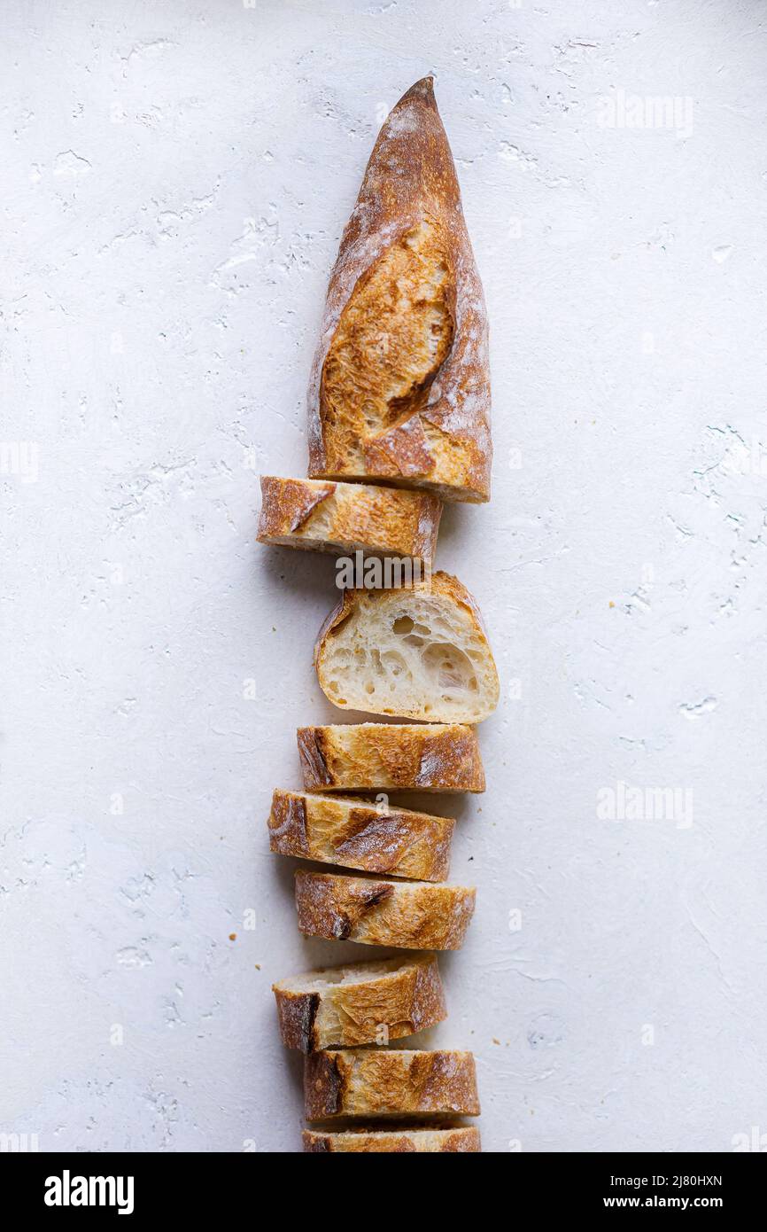 fresh french baguette slices arranged in a loaf on a white background ...