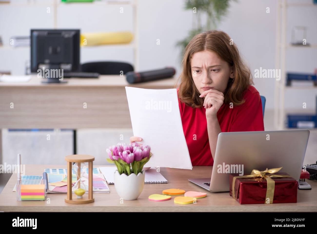 Young female designer celebrating Christmas at workplace Stock Photo