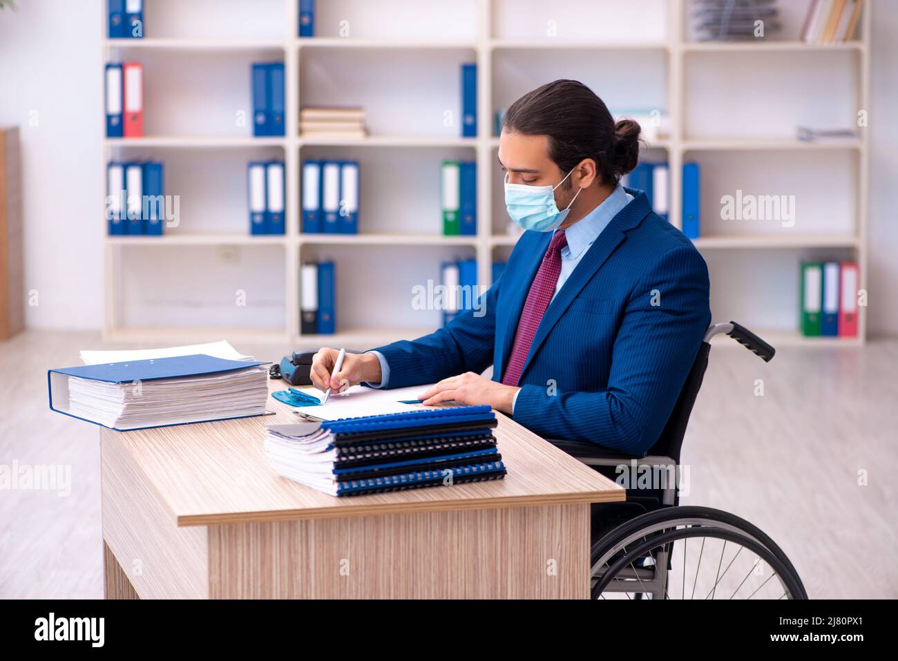 Young male disabled employee during pandemic at workplace Stock Photo ...