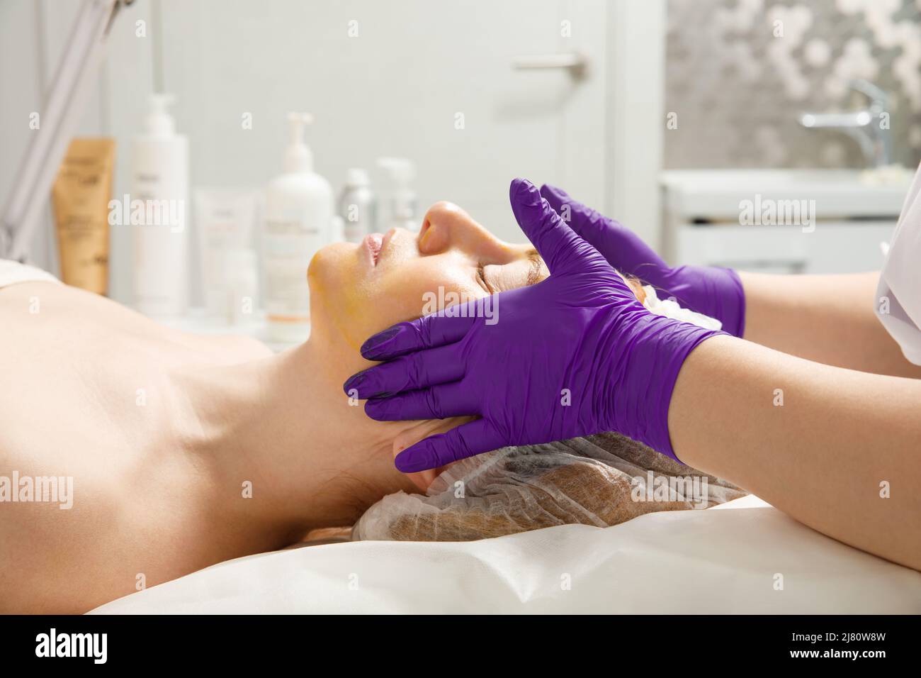 A woman gets a facial massage at a cosmetology clinic. Stock Photo