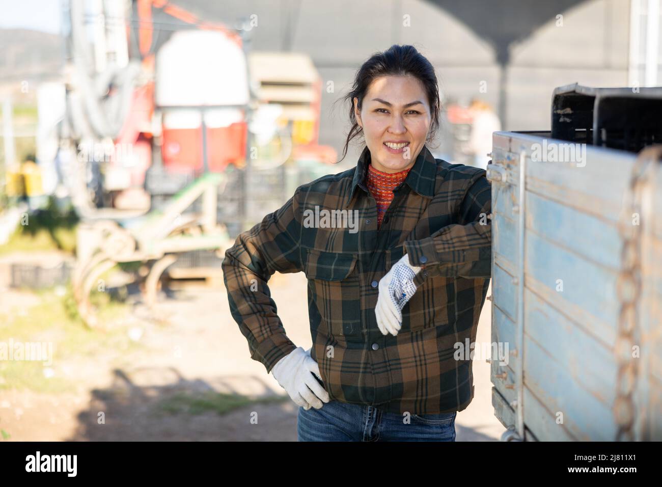 Portrait of positive female tractor driver in farm backyard Stock Photo
