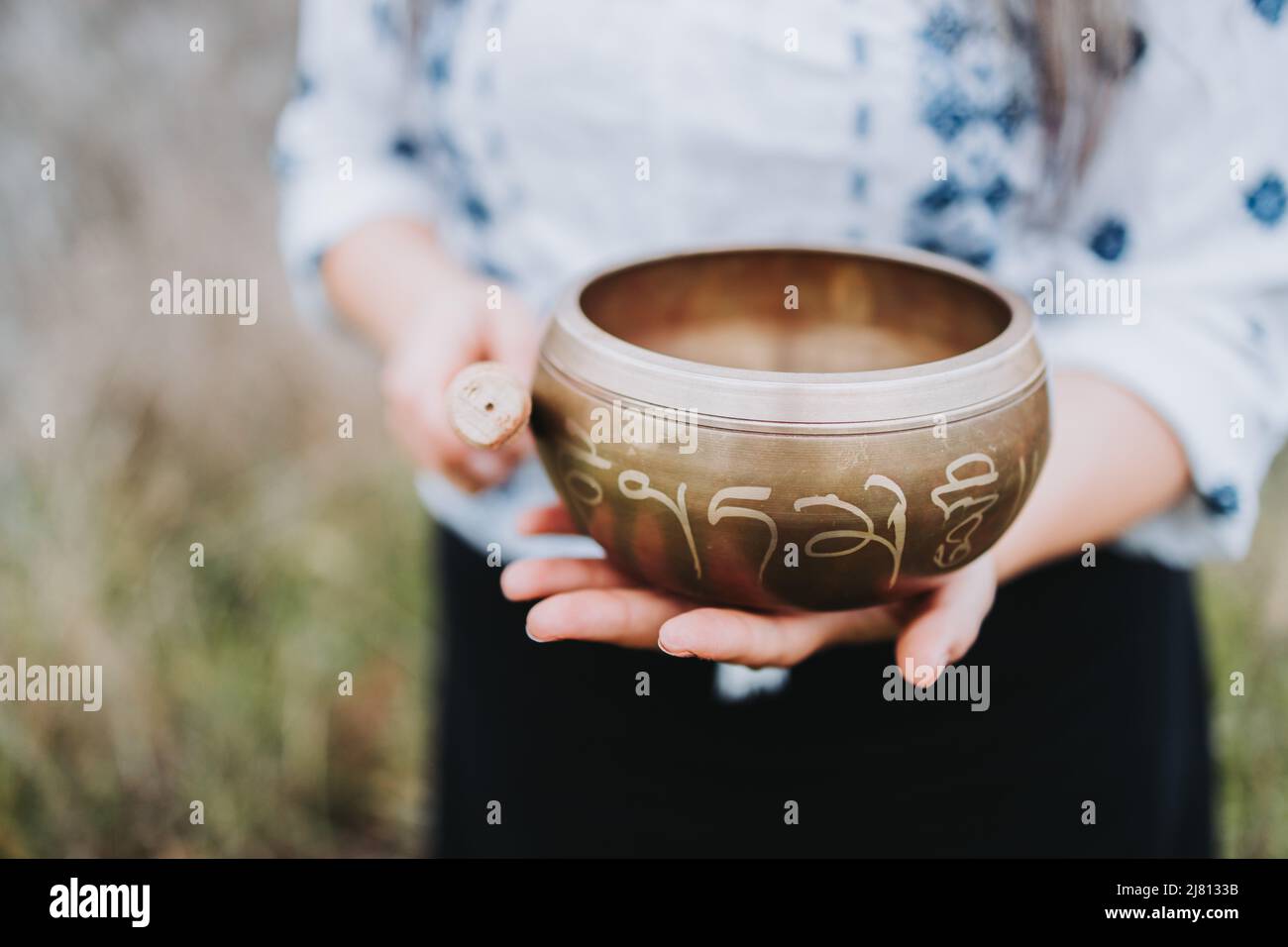 Woman holding a tibetan singing bowl with a wooden stock. Selective focus. Stock Photo