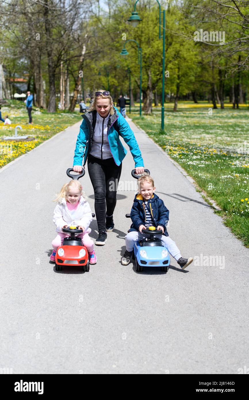 Mom and Kids Are Playing With a Toy Car Outdoors in the Park - A Happy ...