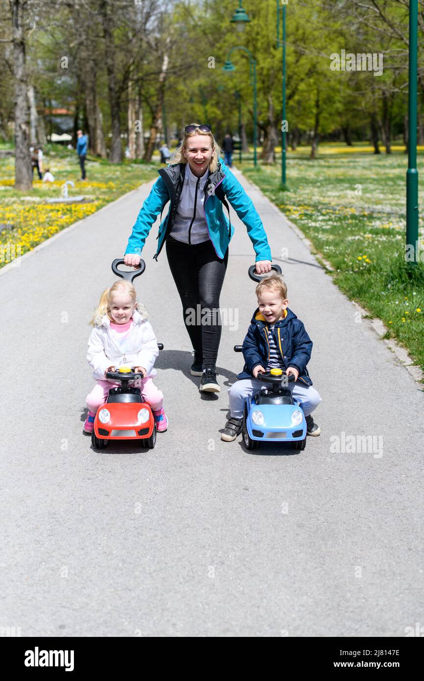 Mom and Kids Are Playing With a Toy Car Outdoors in the Park - A Happy ...