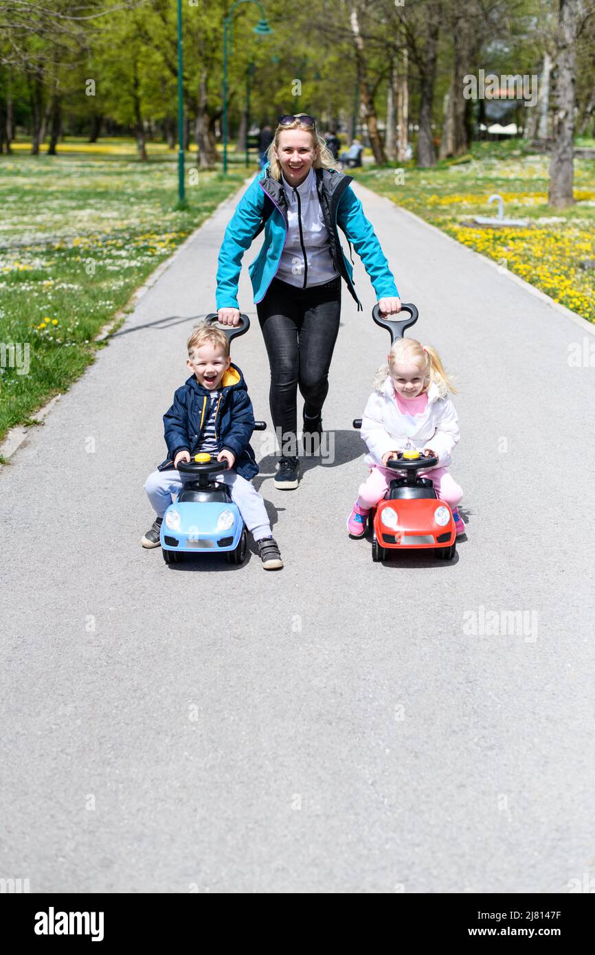 Mom and Kids Are Playing With a Toy Car Outdoors in the Park - A Happy ...
