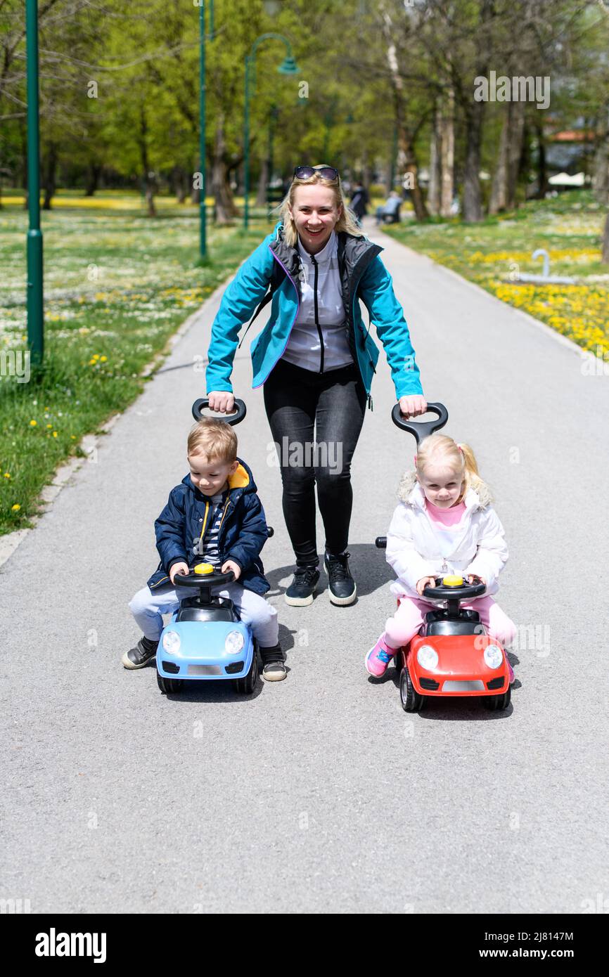 Mom and Kids Are Playing With a Toy Car Outdoors in the Park - A Happy ...