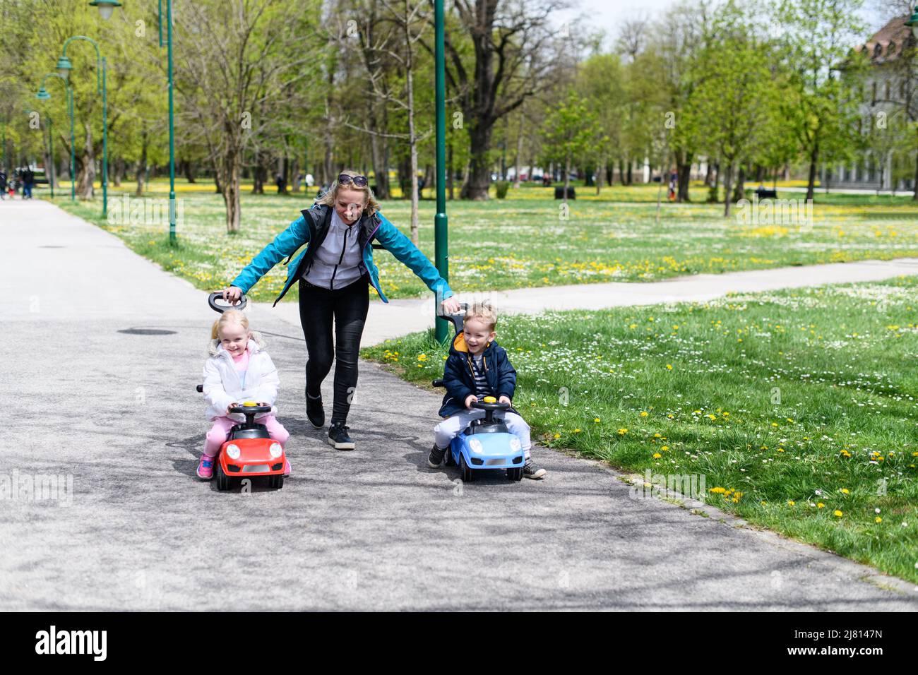 Mom and Kids Are Playing With a Toy Car Outdoors in the Park - A Happy ...