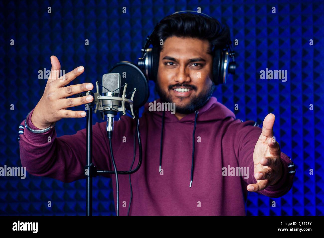 professional singing indian men headphones sound modern studio violet background recording song. Stock Photo