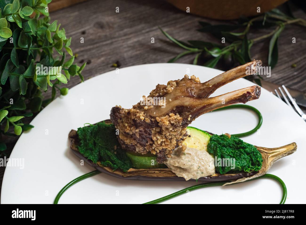 Rack of lamb in nut batter with baked vegetables. Spinach paste and baked eggplant. Molecular food. Stock Photo