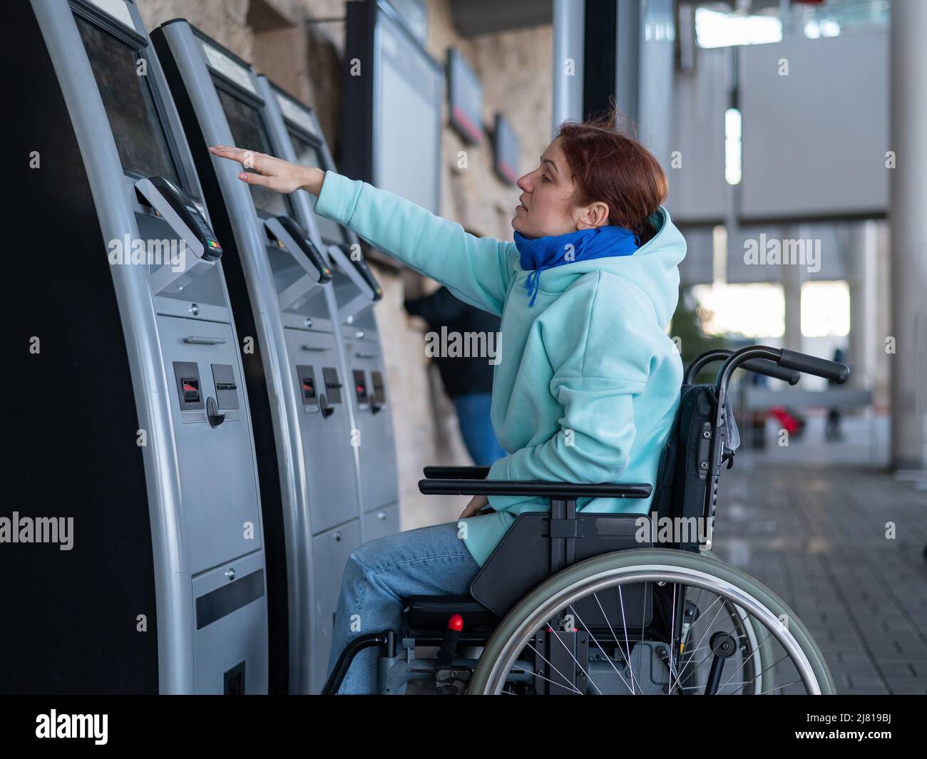 A Caucasian woman in a wheelchair does not reach the selfservice