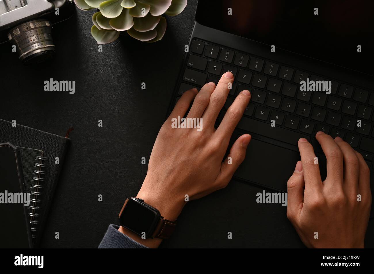 Businessman hands typing on wireless tablet keyboard in his modern black workspace. top view Stock Photo