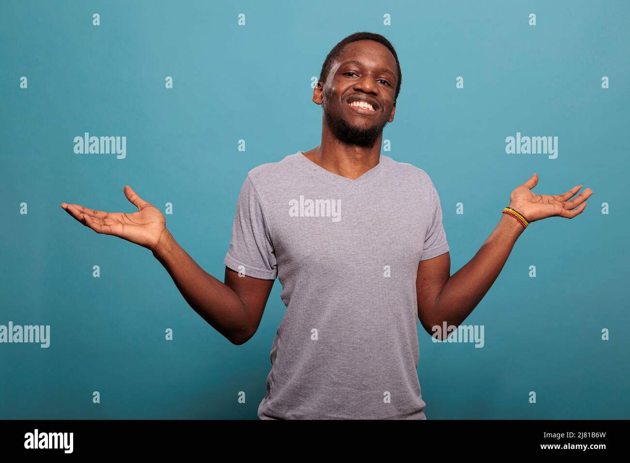 Unsure person rising shoulders and expressing confusion, doing i dont know gesture in studio. Uncertain man feeling indecisive and clueless about answer or solution. Confused guy. Stock Photo