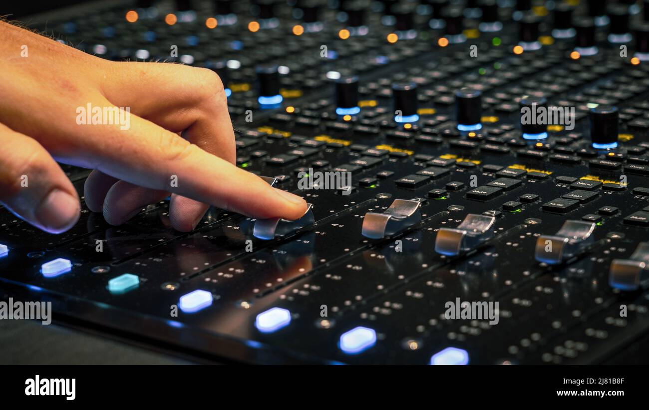 Male hand adjusting the volume on the sound mixing panel Stock Photo