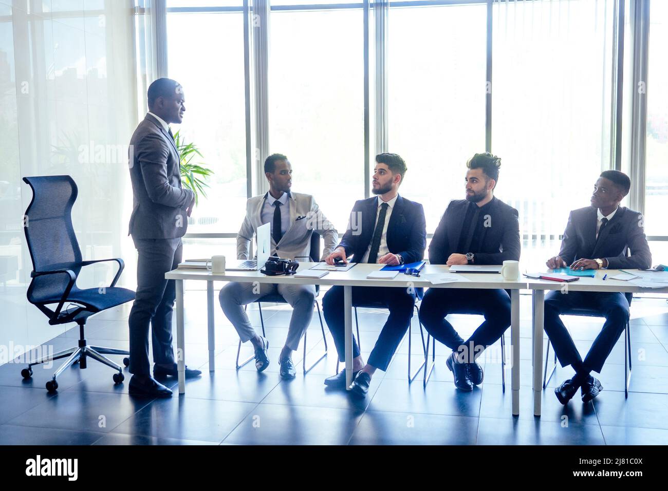 boss afro businessmen talking with arab partners colleague, multiethnic team in the office with panorama window. Stock Photo