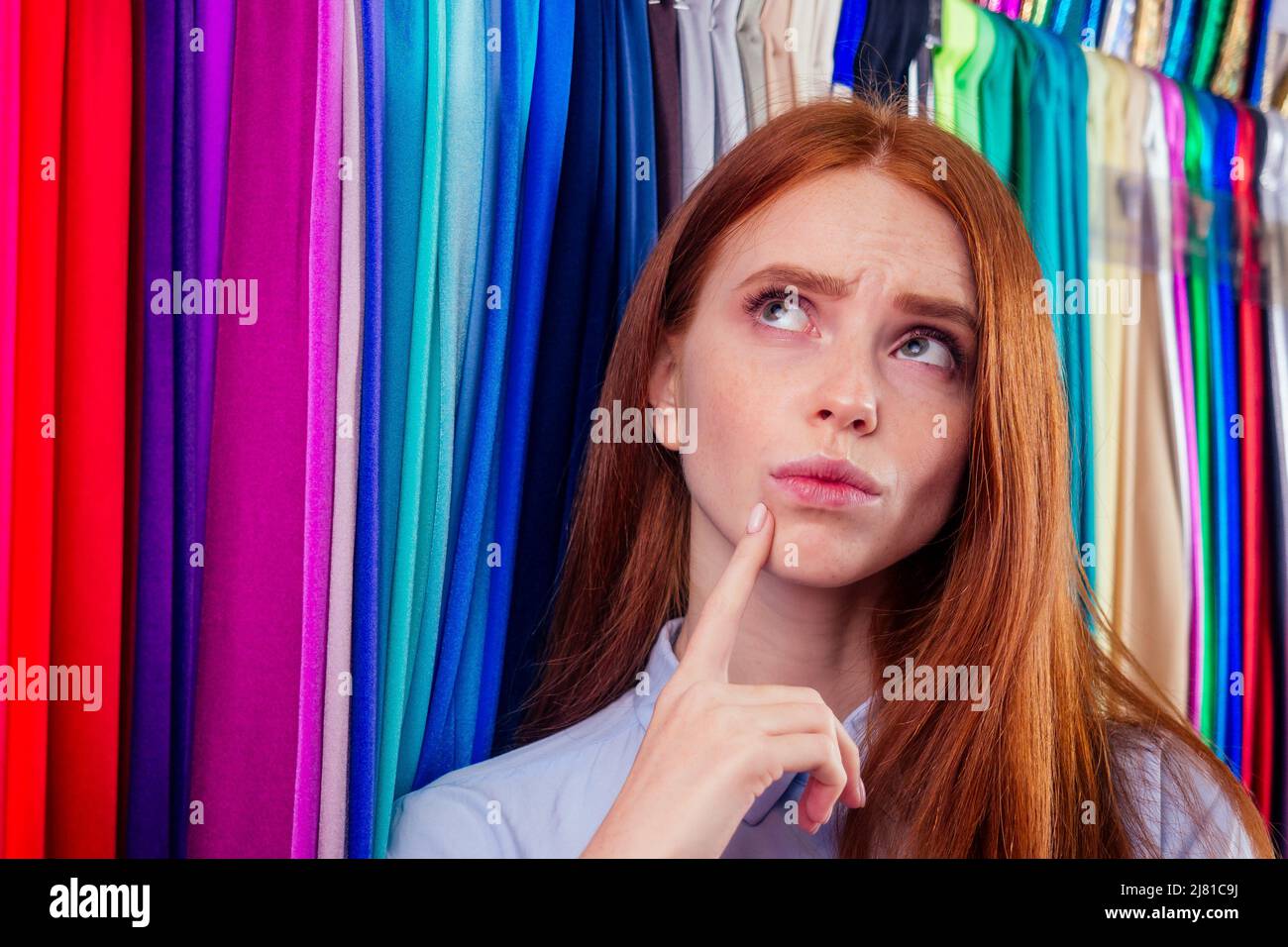 redhair ginger woman choosing color textile in tailor shop for new cloth sewing.she determines the colors that best suit an individual based Stock Photo