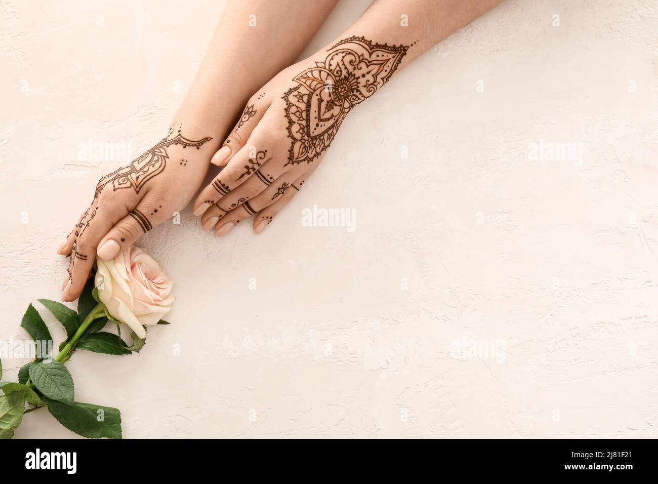 Female hands with henna tattoo and beautiful rose flower on light  background, closeup Stock Photo - Alamy