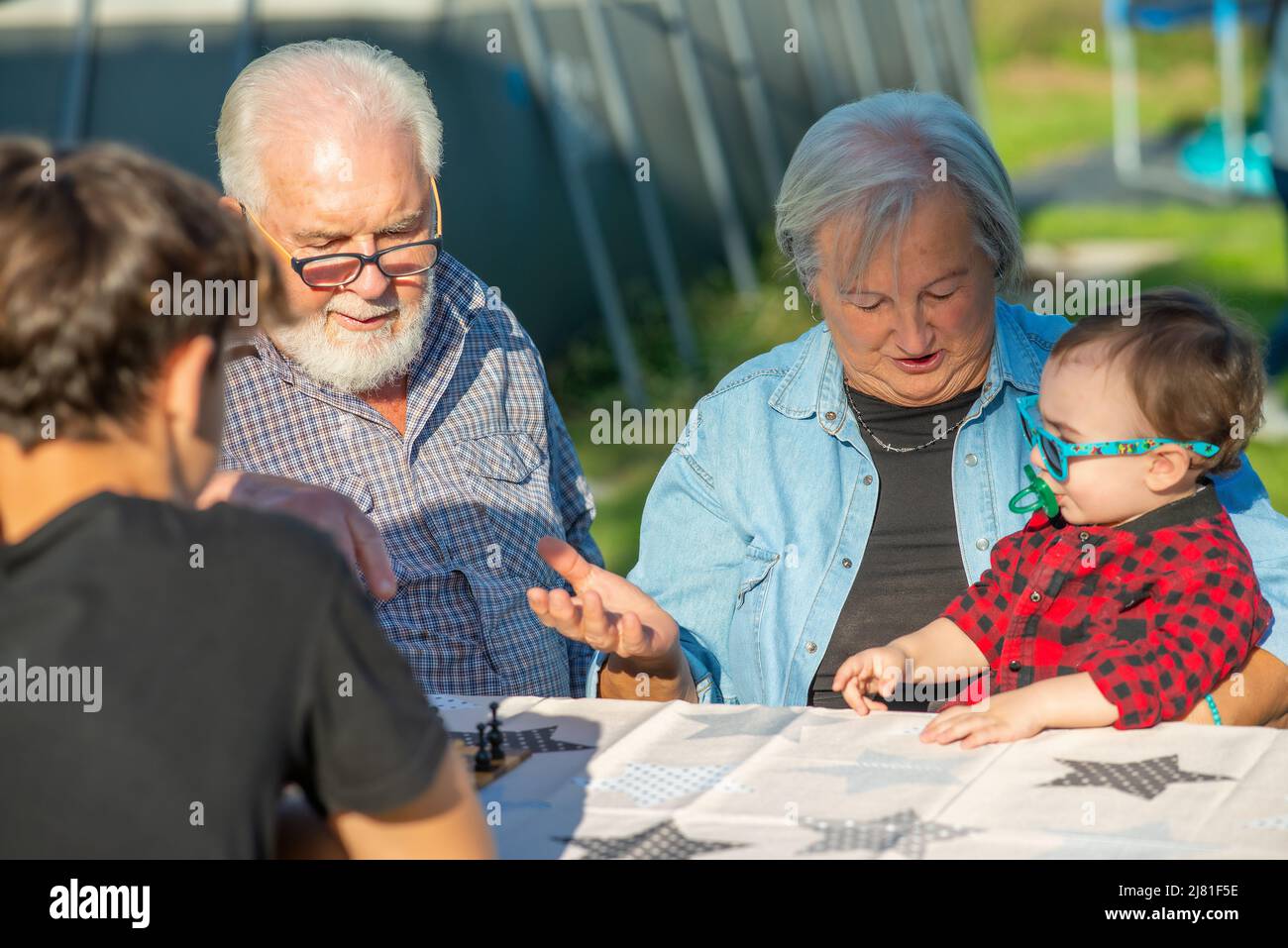 Grandparents and grandchildren playing board games outdoor on a sunny afternoon Stock Photo