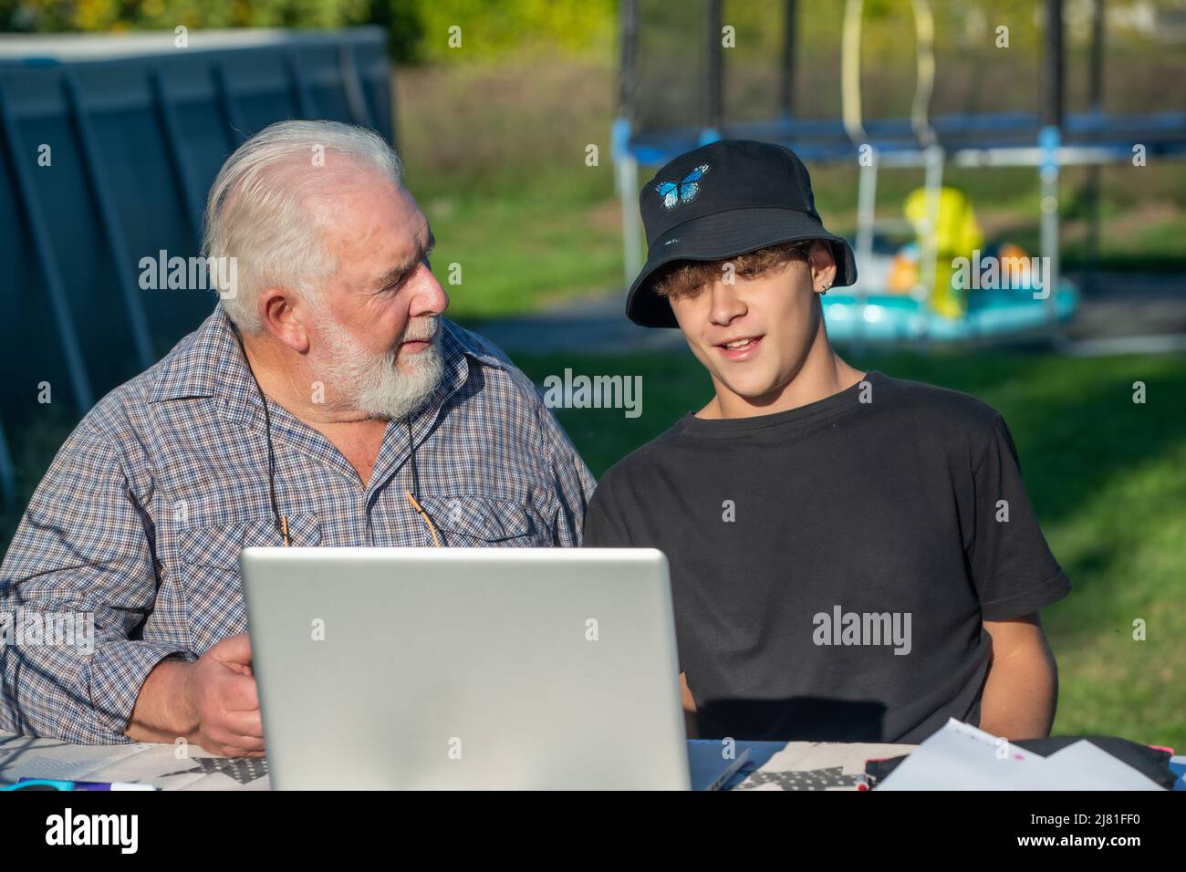 Grandfather explains how to use laptop to his grandson Stock Photo