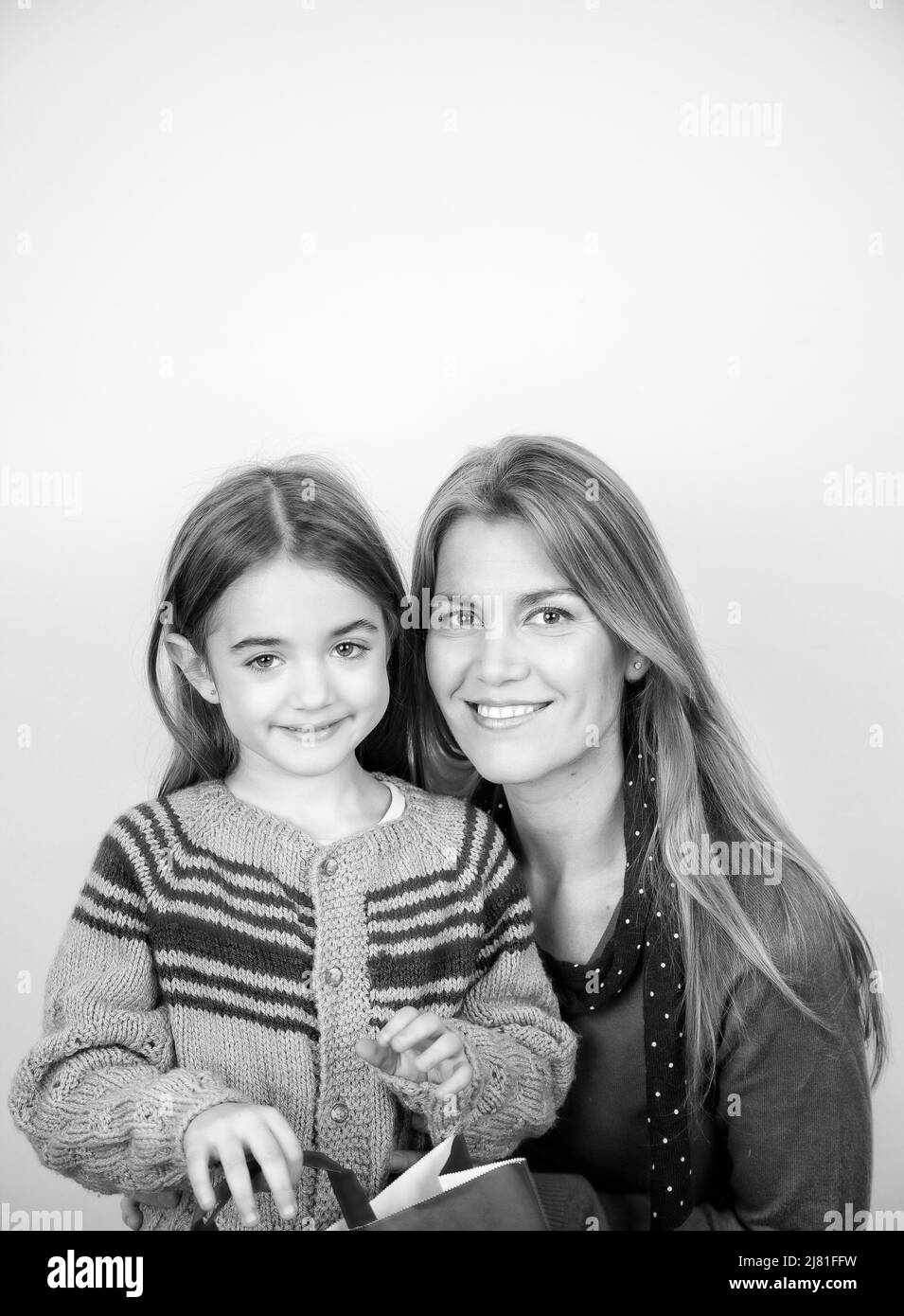 Happy young woman embracing her daughter for Christmas Day, isolated on a white background Stock Photo