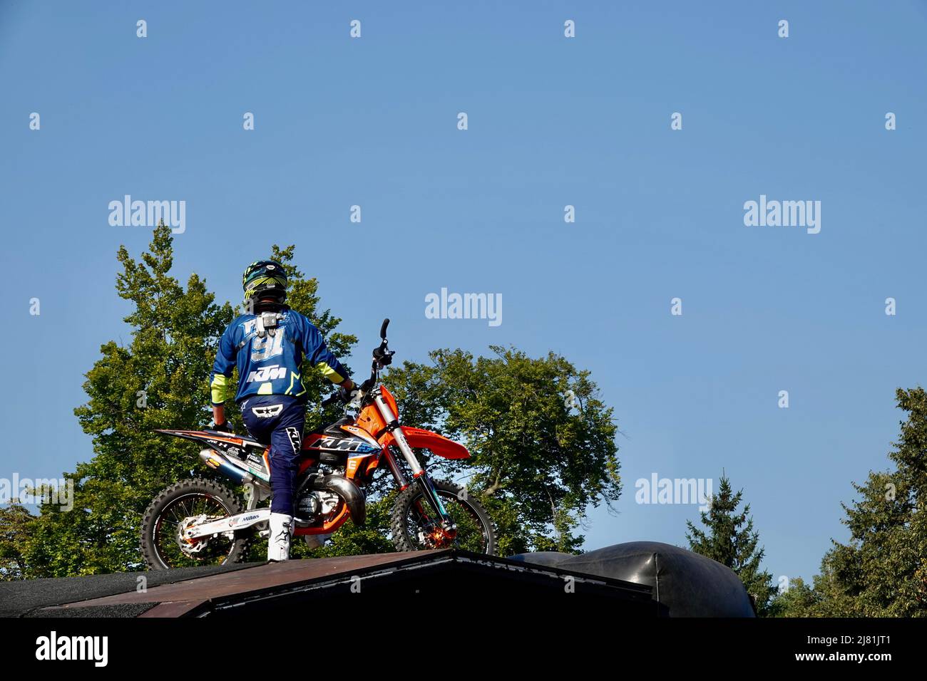 Prague, Czech Republic - September 4 2021: Motocross rider in a blue jumpsuit with a helmet sitting on his motorcycle at the top of the jumping ramp. Stock Photo