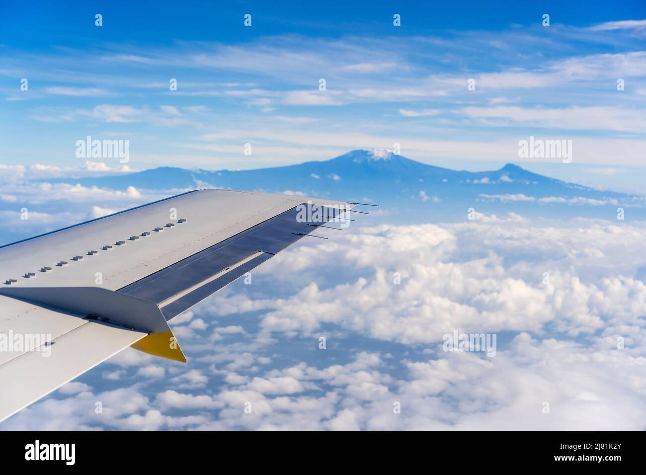 View from the airplane window of the Kilimanjaro volcano in the white clouds in Tanzania, East Africa Stock Photo